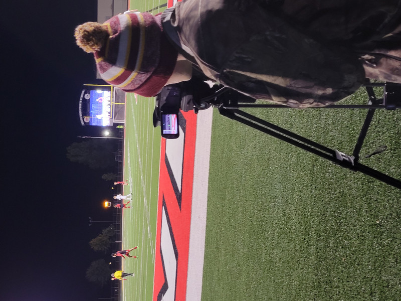 a student operating a camera at a football game