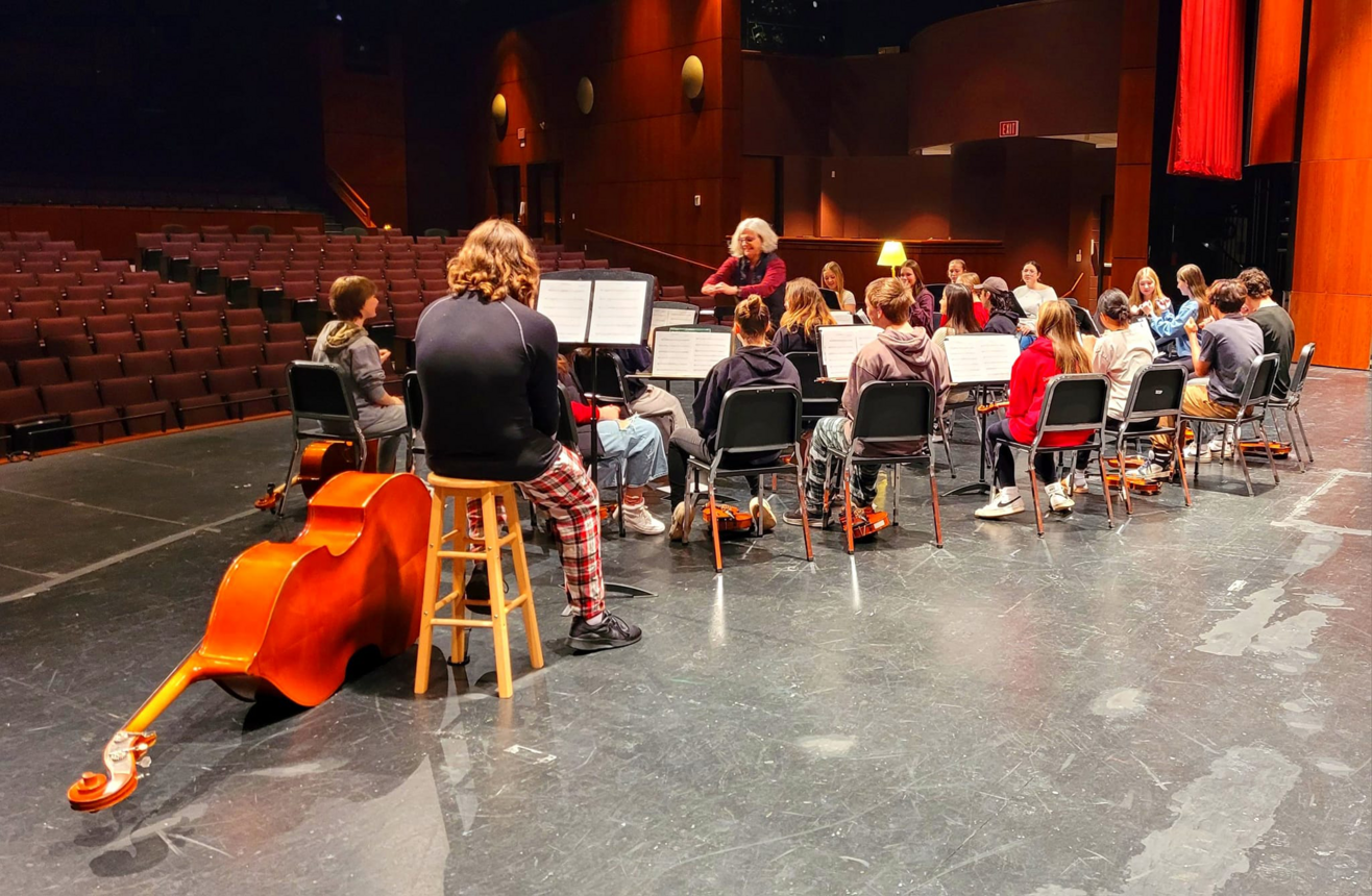 Group of ensemble students relaxing on stage
